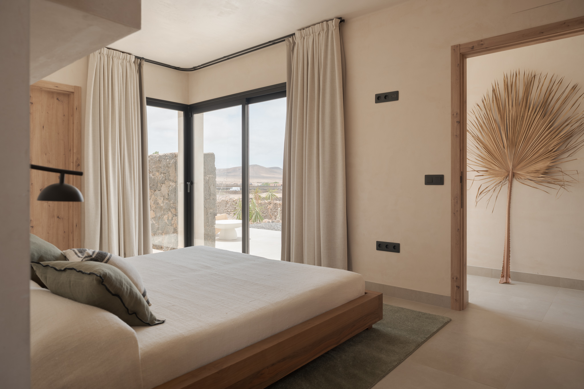 Bedroom with wooden bed frame, mountain views through floor-to-ceiling glass doors